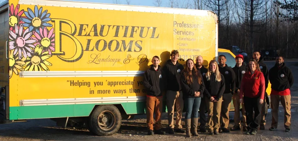 The Beautiful Blooms, LLC team by work trucks in Menomonee Falls, WI.