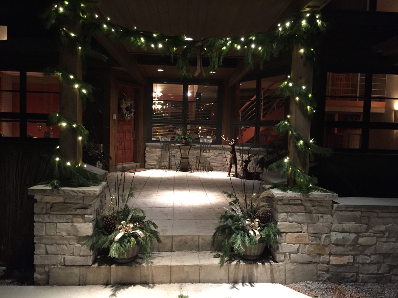 An inviting entrance adorned with festive lights, garlands, and holiday plants, captured during the evening, exudes warmth and seasonal cheer.